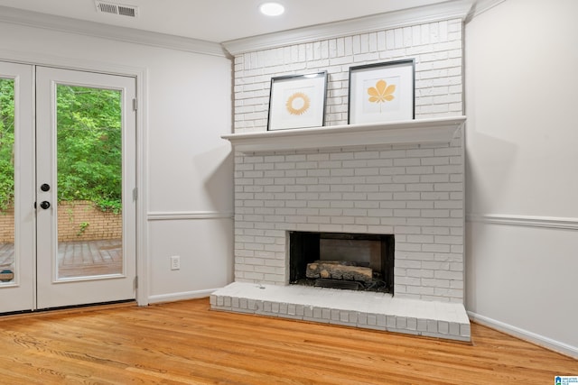 unfurnished living room featuring wood finished floors, visible vents, ornamental molding, baseboards, and a brick fireplace