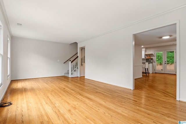 unfurnished living room with french doors, light wood-style floors, stairs, and crown molding