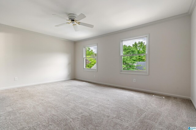 carpeted spare room with visible vents, a ceiling fan, baseboards, and ornamental molding