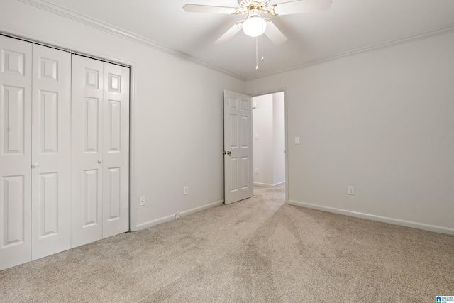 unfurnished bedroom featuring a closet, ceiling fan, light carpet, baseboards, and ornamental molding