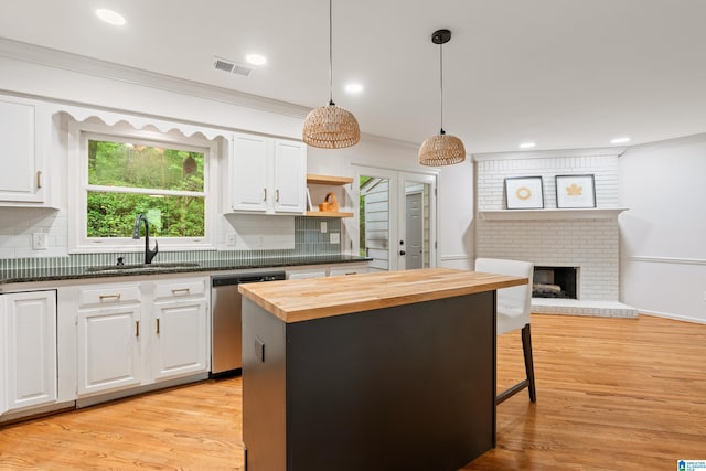 kitchen with stainless steel dishwasher, a sink, butcher block counters, backsplash, and visible vents