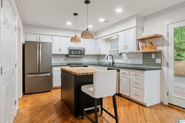 kitchen with stainless steel appliances, wood counters, a sink, and white cabinetry