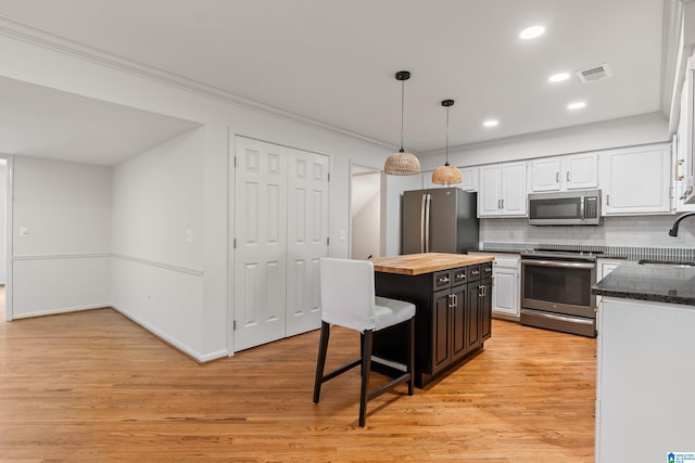 kitchen featuring white cabinets, stainless steel appliances, light wood finished floors, a sink, and butcher block counters