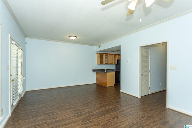 unfurnished living room with a sink, ceiling fan, dark wood-type flooring, crown molding, and baseboards