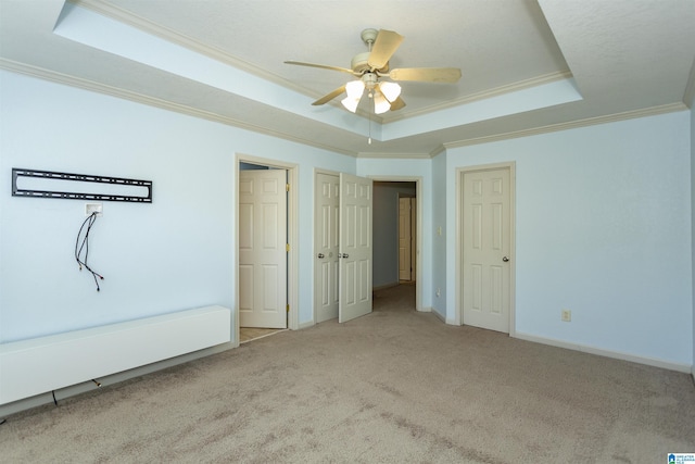 unfurnished bedroom with carpet, crown molding, a tray ceiling, and baseboards