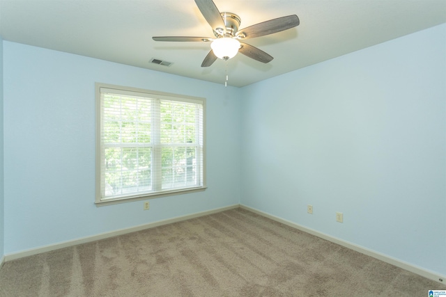 carpeted spare room with visible vents, a ceiling fan, and baseboards