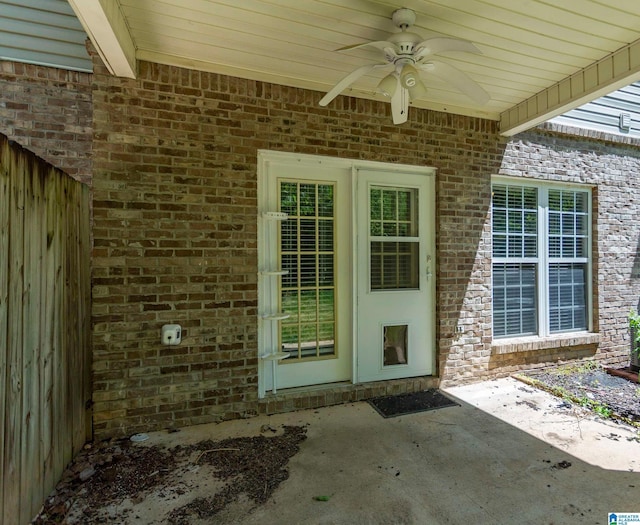 entrance to property featuring brick siding, a ceiling fan, and a patio area