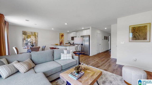 living room with light wood-type flooring, baseboards, recessed lighting, and visible vents
