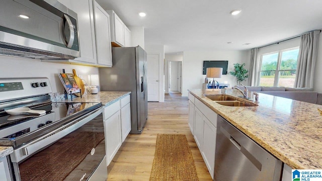 kitchen featuring stainless steel appliances, a sink, and white cabinetry