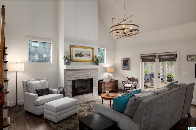 living area with a brick fireplace, a high ceiling, an inviting chandelier, and dark wood finished floors