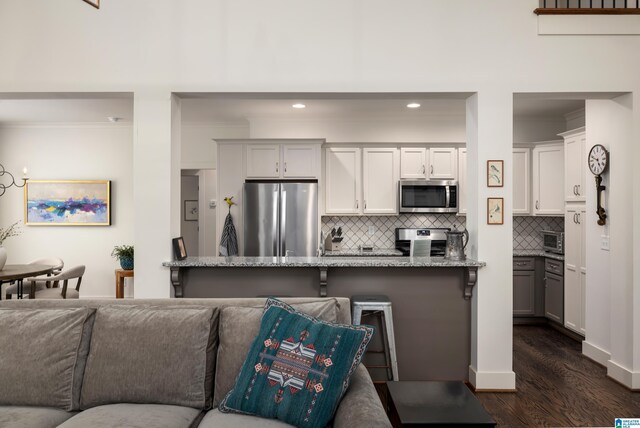 kitchen featuring light stone countertops, stainless steel appliances, dark wood-type flooring, backsplash, and ornamental molding
