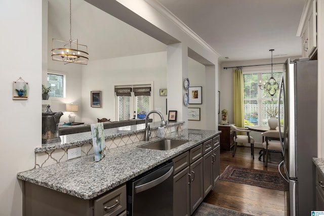 kitchen with appliances with stainless steel finishes, dark wood-type flooring, a notable chandelier, and a sink