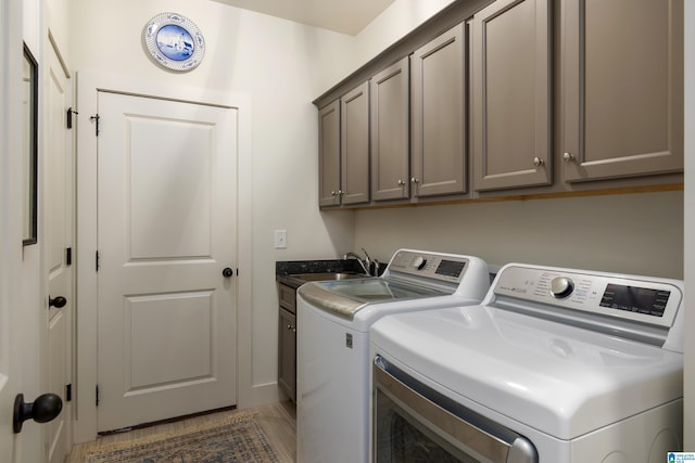 washroom with washing machine and clothes dryer, cabinet space, and a sink