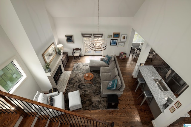 living room featuring baseboards, wood finished floors, a notable chandelier, and a towering ceiling