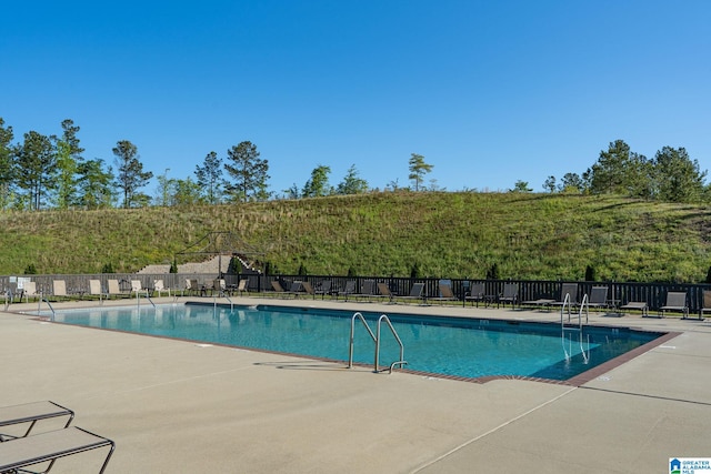 community pool with a patio area and fence