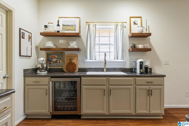 bar with dark wood finished floors, beverage cooler, bar, and a sink