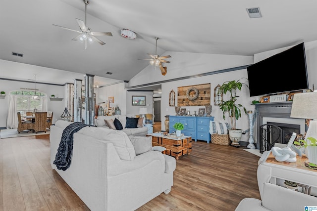 living room with a fireplace with flush hearth, vaulted ceiling, wood finished floors, and ceiling fan