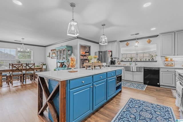 kitchen with light countertops, blue cabinets, crown molding, and stainless steel appliances