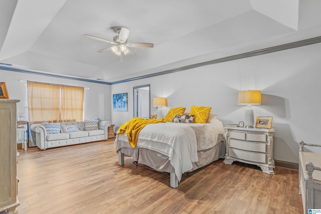 bedroom with a tray ceiling, wood finished floors, and ceiling fan