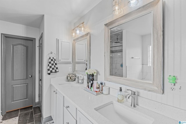full bath with a sink, double vanity, and tiled shower
