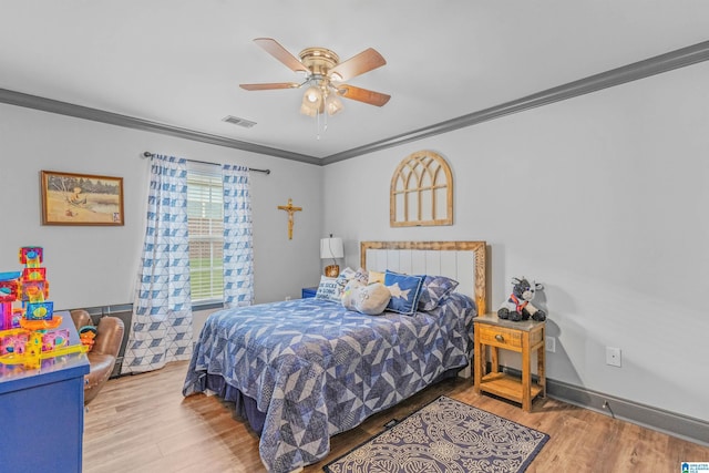 bedroom featuring a ceiling fan, ornamental molding, wood finished floors, and visible vents
