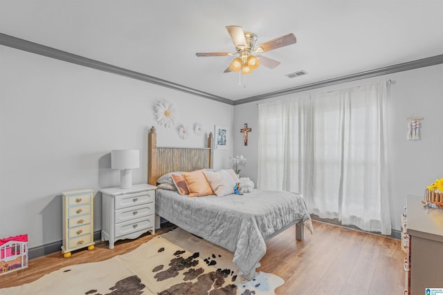 bedroom with light wood finished floors, visible vents, crown molding, and ceiling fan