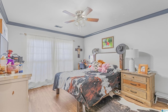 bedroom with light wood-style floors, visible vents, crown molding, and a ceiling fan