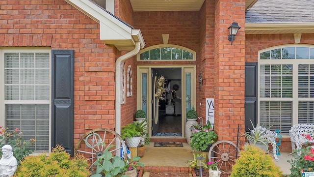 entrance to property with brick siding and a shingled roof