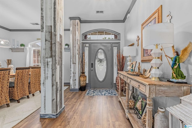 foyer with ornamental molding, wood finished floors, and visible vents