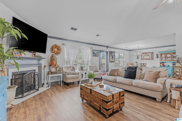 living area with visible vents, lofted ceiling, wood finished floors, and ornamental molding
