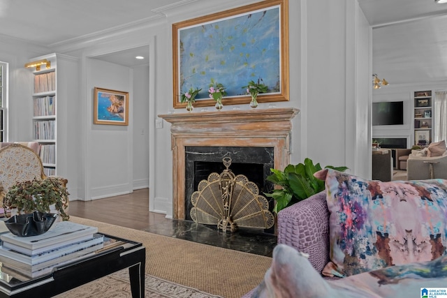 living area with baseboards, a high end fireplace, built in features, and crown molding