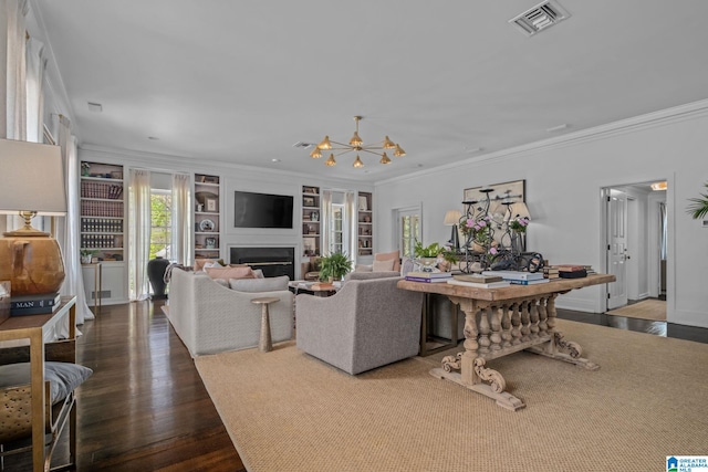 living area with a chandelier, a fireplace, built in features, visible vents, and wood finished floors