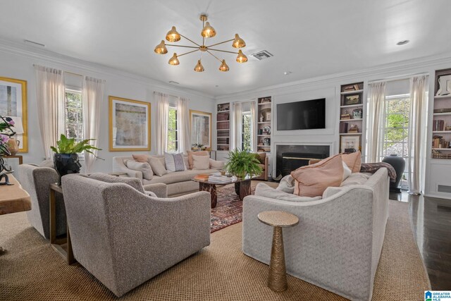 living area with a wealth of natural light, a high end fireplace, crown molding, and an inviting chandelier