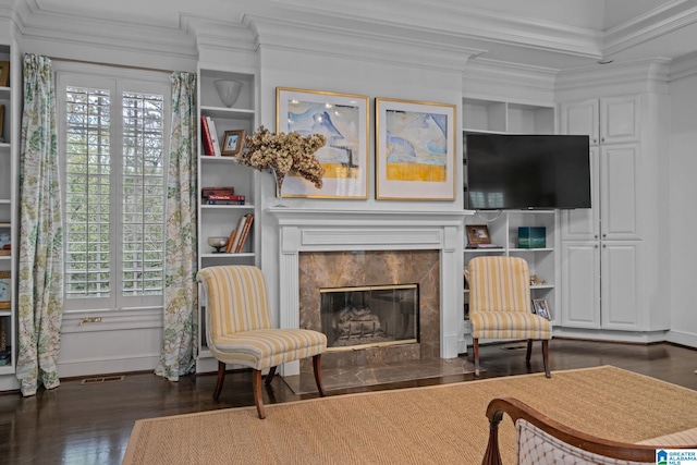 living area with ornamental molding, a high end fireplace, wood finished floors, and baseboards