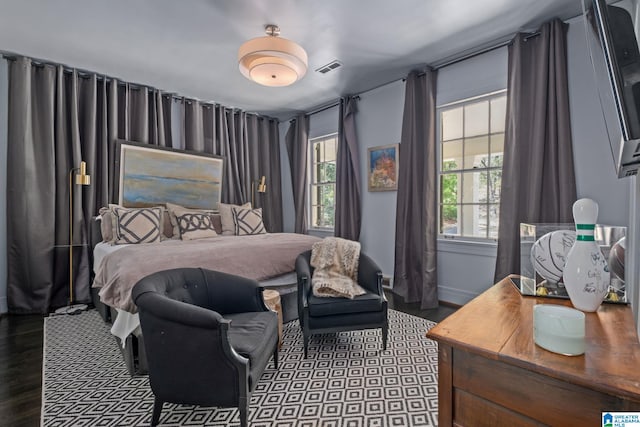 bedroom with dark wood-style floors, visible vents, and baseboards