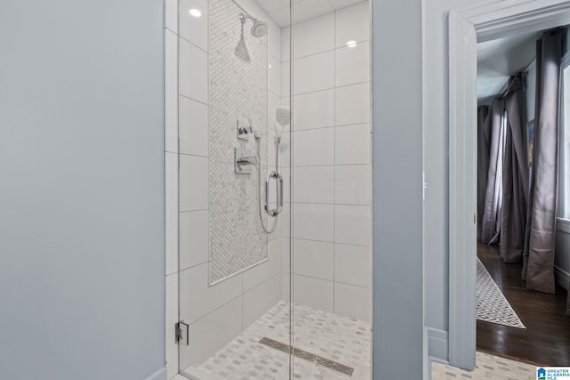 bathroom with a shower stall, wood finished floors, and baseboards