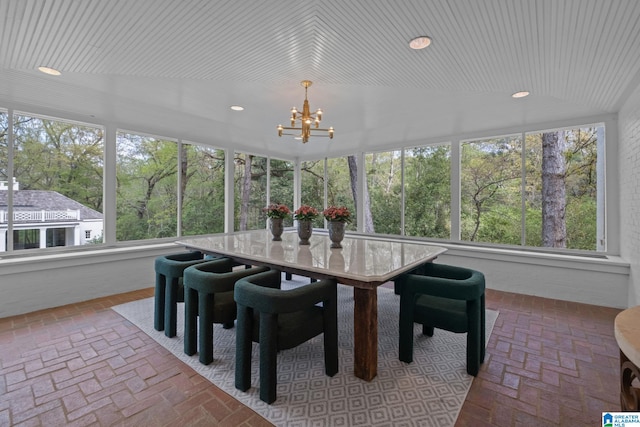 sunroom featuring recessed lighting, brick floor, and a chandelier