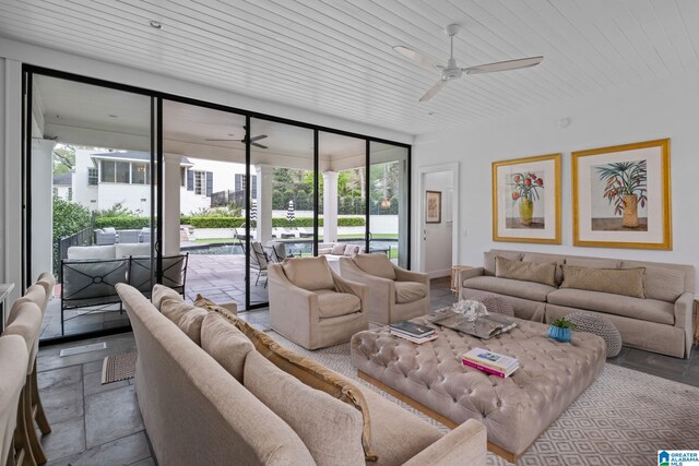 living room with wood ceiling, stone tile flooring, and a ceiling fan