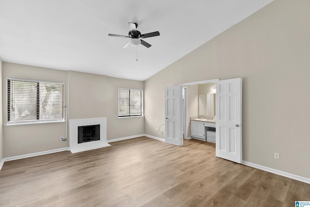 unfurnished living room with baseboards, ceiling fan, a fireplace with raised hearth, and plenty of natural light