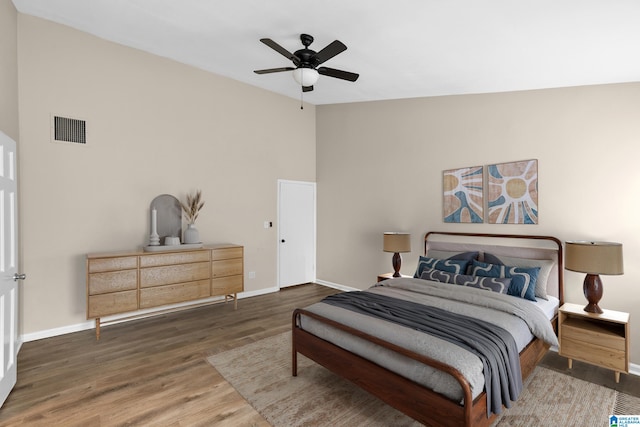 bedroom with wood finished floors, visible vents, vaulted ceiling, and baseboards