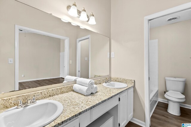 bathroom featuring double vanity, a sink, wood finished floors, and visible vents