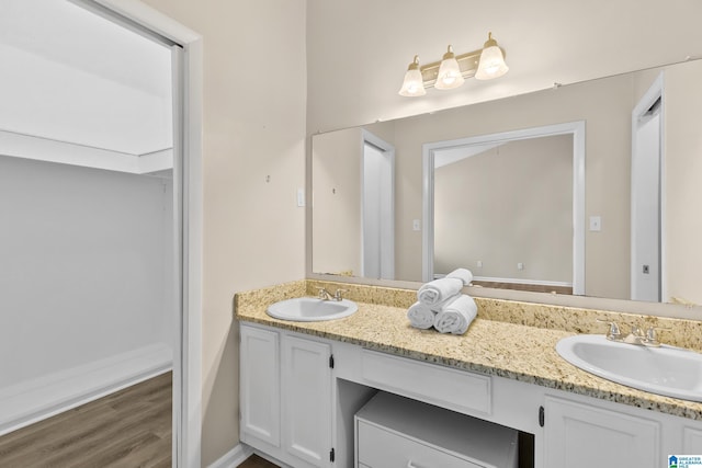 full bathroom with wood finished floors, double vanity, and a sink