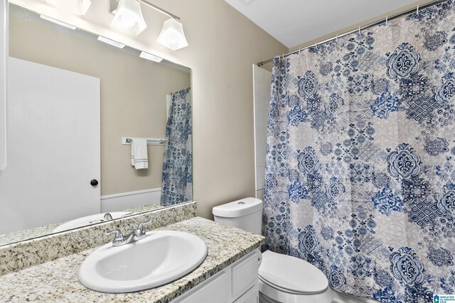 bathroom featuring toilet, vanity, and a shower with shower curtain