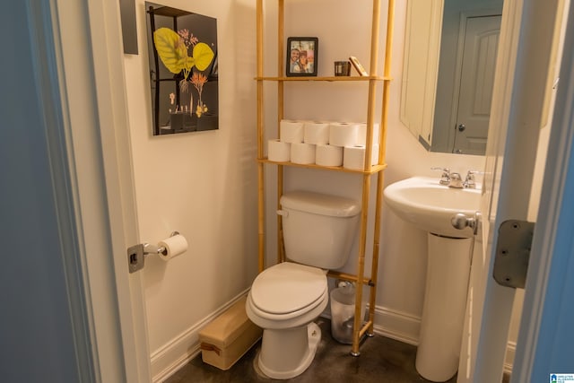bathroom with toilet, a sink, and baseboards