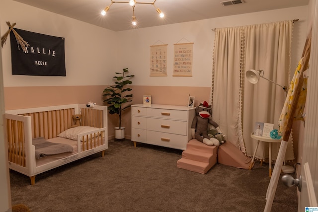 bedroom with visible vents, a nursery area, and carpet