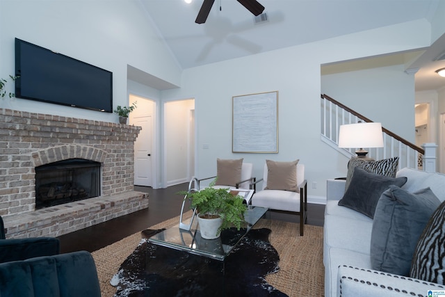 living room with a fireplace, ceiling fan, stairs, visible vents, and wood finished floors