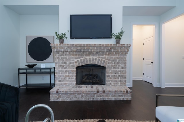 living room featuring a brick fireplace, wood finished floors, and baseboards