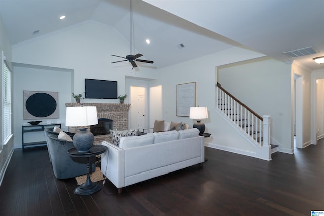 living area featuring a brick fireplace, dark wood-style flooring, visible vents, and stairs