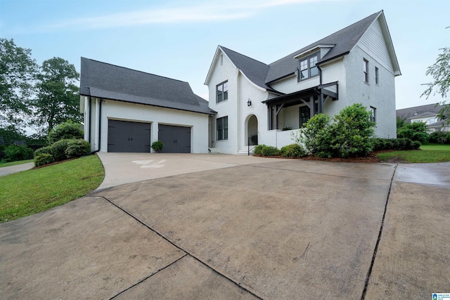 modern inspired farmhouse with roof with shingles, a front lawn, concrete driveway, and an attached garage