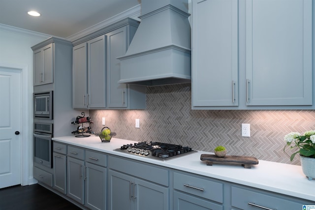 kitchen with appliances with stainless steel finishes, light countertops, custom range hood, and backsplash
